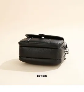Detailed bottom view of a black faux leather crossbody bag with lychee texture and fine stitching