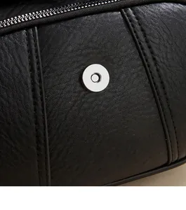 Detail of lychee textured black leather bag showing silver magnetic snap and metal zipper