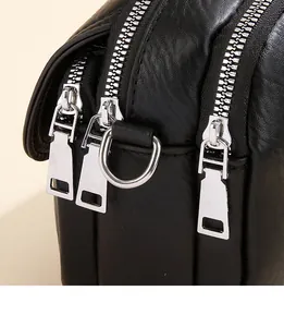 Detailed macro view of triple silver zippers and D-ring on black textured leather bag