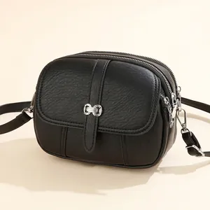 Classic black crossbody round bag in lychee texture with silver bow metal clasp detail