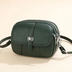 Deep green textured leather crossbody bag with three zipper compartments and silver buckle