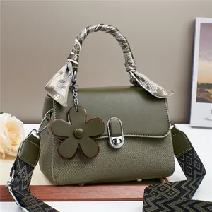 Detail of olive green pebbled leather bag with silk scarf handle and floral charm