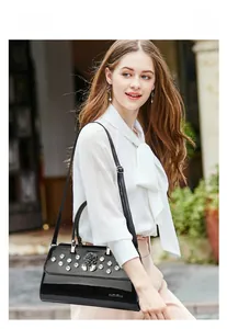 Detail of elegant black patent leather handbag with rhinestone accents and 3D flower