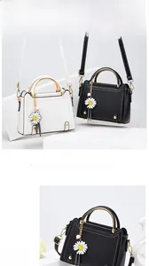 Detail of metal ring handles and daisy tassel charms on black and white leather handbags