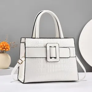Detail of white crocodile pattern tote bag with top handle and golden strap buckle