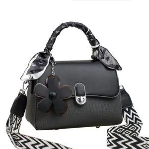 Elegant black woven leather handbag with floral pendant and patterned silk scarf detail