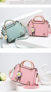 Detail of textured leather crossbody bag with daisy charm and gold hardware accents