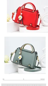 Detail view of red and green square handbags with daisy charms and gold metal handles