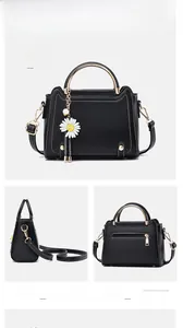 Detailed views of a black litchi leather handbag with golden ring handle and daisy charm