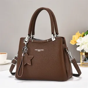 Close-up of brown pebbled tote bag featuring star charm and silver hardware details