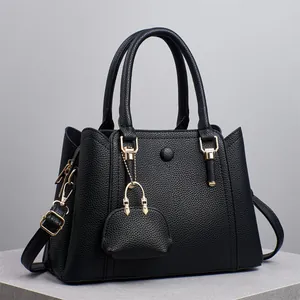 Schwarze Tragetasche aus strukturiertem Leder mit Gold-Hardware und Mini-Taschenanhänger