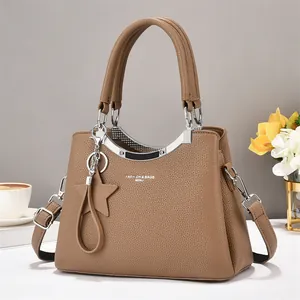 Detail of brown leather handbag featuring silver hardware and star charm accessory