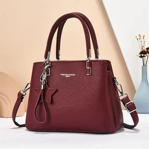 Wine red pebble leather handbag with adjustable strap and decorative tassel charm