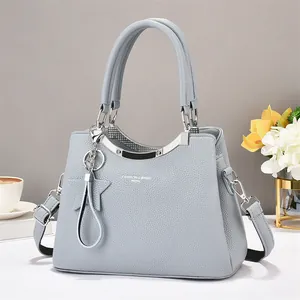 Detail of light gray lychee grain leather tote bag with silver hardware and star pendant