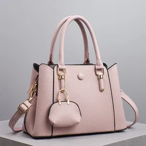 Detail der pinkfarbenen Handtasche mit Lederstruktur, Mini-Anhänger und goldenen Beschlägen