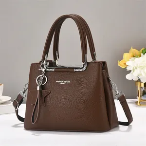 Detailed macro shot of lychee grain faux leather texture and silver hardware on a brown bag