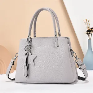 Detail of grey lychee leather handbag with star charm and detachable shoulder strap