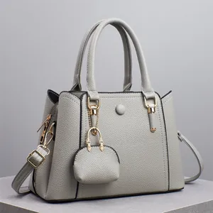 Detail der cremeweißen Handtasche mit Litschi-Struktur, Goldzipper und Mini-Münzgeldbörse