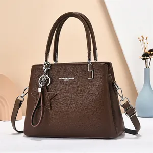Close-up of brown litchi leather tote bag with silver hardware and star charm accessory