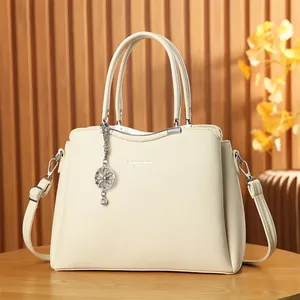 Détail d'un sac à main blanc cassé avec pendentif fleur et texture en similicuir grainé