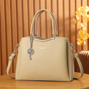 Détail d'un sac à main beige en similicuir grainé avec pendentif et finitions argentées