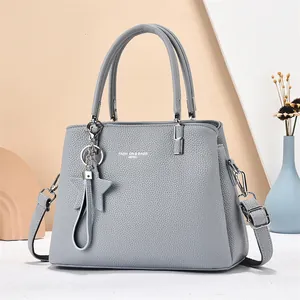 Detail of grey lychee leather tote bag with silver hardware and star charm pendant