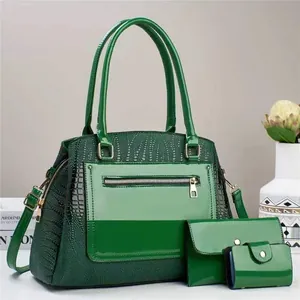 Detail of green crocodile texture on large tote bag with zipper and metal accents
