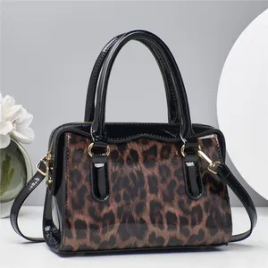 Detail der Handtasche mit Leopardenmuster, schwarzen Lackgriffen und goldener Hardware