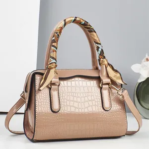 Détail du sac polochon beige à motif crocodile avec foulard en soie et bandoulière