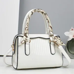 Close-up of white embossed tote bag with black trim and elegant silk scarf handle decoration
