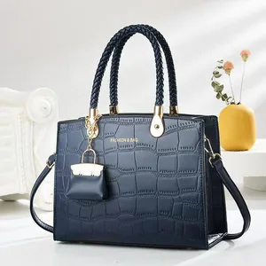 Close-up of crocodile embossed handbag with braided handles and golden metal accents
