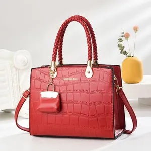 Red crocodile pattern handbag with dual handles and mini charm on a stylish background