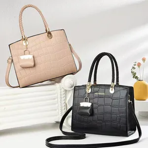 Close-up of crocodile embossed leather tote bag with woven handles and gold hardware