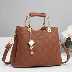 Close-up of brown checkered embossed handbag featuring gold hardware and elegant charm