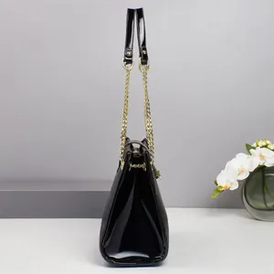 Seitenansicht der schwarzen Handtasche mit glänzendem Lackleder und goldener Kettenstruktur