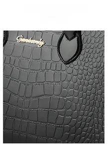 Detail of black crocodile texture embossed leather bag with gold metal logo plaque