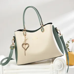 Elegante Handtasche in Beige und Salbeigrün mit goldenen Beschlägen und Herz-Anhänger