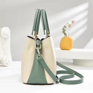 Elegante zweifarbige Lederhandtasche in Creme und Grün mit goldenen Beschlägen und Gurt
