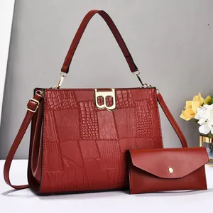 Detail view of burgundy crocodile pattern leather bag set with gold B buckle and clutch