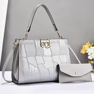 Detail of silver crocodile pattern patchwork bag with golden metal B-buckle and envelope pouch