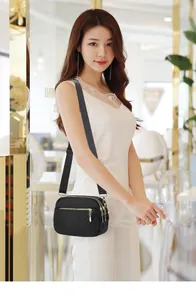 Close-up of quilted black nylon crossbody bag with three golden zippers and wide strap