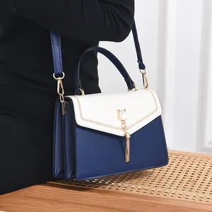 Contrast color crossbody bag with cat-shaped hardware and tassel on a woven chair