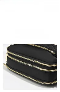 Detail of black quilted nylon crossbody bag featuring smooth triple golden metal zippers
