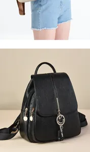 Detail of black faux leather backpack with litchi texture and metallic smile pendant