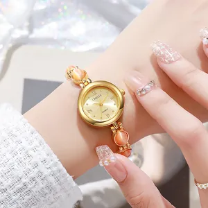 Elegante reloj de pulsera dorado para mujer con piedras ojo de gato y esfera champán