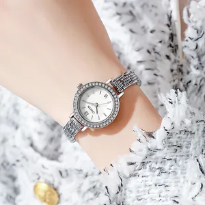 Elegant women's watch with rhinestone bezel and silver metal strap on tweed background