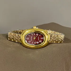 Close-up of vintage gold ladies watch with burgundy oval dial and Roman numerals