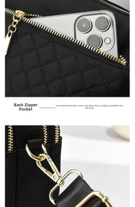 Detailed macro view of black quilted crossbody phone bag with rear zipper pocket and gold hardware