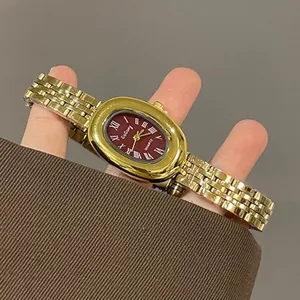Close-up of vintage gold quartz watch with a deep red oval dial and Roman numerals