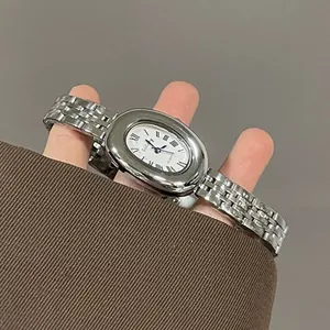Close-up of vintage oval silver quartz watch on wrist with Roman numerals dial